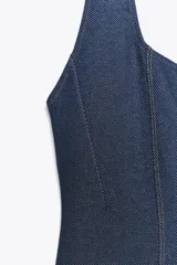Mono largo de denim azul, con cuello halter y escote redondo. Detalle de pespuntes a contraste. Espalda descubierta. Pierna ancha. Cierre en cuello.