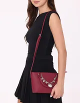 Cartera tipo city de cuerina color bordó, con doble asa corta y correa larga regulable. Incluye charm decorativo con cadena plateada y dijes colgantes.
