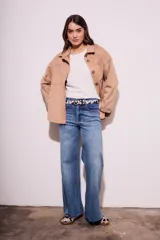 Sobrecamisa negra de gamuza vegana con calce oversize, cuello camisero, cierre con botones a presión, mangas largas con puños abotonados y bolsillos de parche en el pecho.