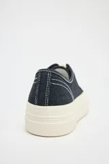 Zapatillas bajas de denim azul oscuro con cordones blancos y suela de plataforma color crema.