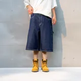 Bermuda de jean azul oscuro, corte ancho, con bolsillos delanteros y traseros, y un bolsillo lateral con etiqueta de la marca.