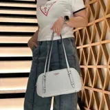 Cartera de hombro Guess modelo Cerelia, color blanco con logo dorado estampado. Tiene correa ajustable y cierre superior.