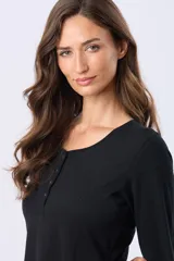 Remera negra de manga larga, lisa, con cuello redondo y una hilera de botones en la parte frontal.