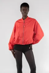 Campera bomber color beige, corte regular, con cierre frontal con cremallera visible, cuello acanalado, puños y bajo elásticos fruncidos, hombro caído, bolsillos de ribete verticales y bolsillo utilitario con cremallera en la manga.