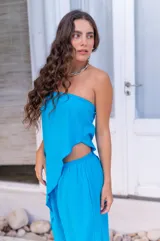 Top strapless de color turquesa confeccionado en muselina de crepe. Presenta un diseño asimétrico con un bajo irregular y una abertura lateral.