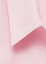 Camisa rosada de algodón con corte recto, cuello camisero, manga larga con puños abotonados, bolsillo de parche en el pecho y cierre frontal con botones.