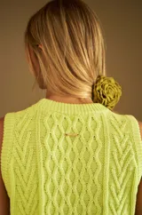 Chaleco marrón de punto con diseño trenzado, cuello redondo y sisas con volantes celestes.