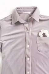 Pijama celeste de terciopelo, compuesto por una camisa de manga larga con botones y vivo blanco, bolsillo en el pecho y un pantalón recto con elástico en la cintura.