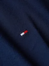 Camisa azul marino de corte slim, confeccionada en tejido dobby de algodón con Flex Technology, cuello abotonado, puños redondeados con dos botones y logo de Tommy Hilfiger bordado en el pecho.