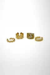 Set de cuatro anillos dorados con diferentes diseños: uno con bolitas, uno con forma de moño, uno con calados y uno con forma de flores.