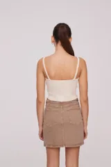 Top de bretel fino color crema, liso, al cuerpo y con escote en V.
