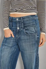 Jean de denim azul oscuro con tiro medio y pierna recta. Presenta un diseño diferencial de doble cintura superpuesta con cierre y botón metálico.