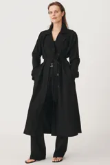 Trench negro oversize con cuello solapa, manga larga con trabilla y botón, bolsillos delanteros, cinturón ajustable con lazadas, abertura en la espalda y cierre frontal con botones ocultos por solapa.