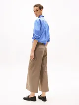 Pantalón de vestir color beige, de corte tobillero y pierna ancha. Confeccionado en tejido antiarrugas de mezcla de poliéster, viscosa y elastano. Presenta cierre de cremallera con enganche oculto, raya marcada en la parte delantera y trasera, y dos bolsillos traseros de ojal.