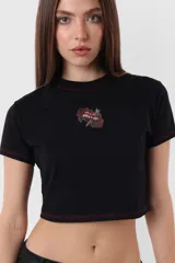 Remera corta blanca tipo baby tee, de cuello redondo y mangas cortas, confeccionada en jersey de algodón. Detalle de costuras rojas en toda la prenda y estampa de flecha con rosa en el delantero.