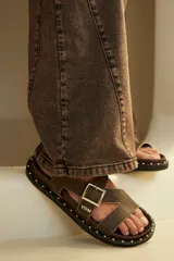 Sandalias de cuero color marrón con tachas en la suela y ajuste de hebilla en el empeine.