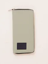 Billetera grande color verde claro, con cierre de cremallera y parche de goma con logo en la parte inferior.