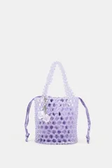 Bolso mini tipo saca cilíndrica con cuerpo de cuentas brillantes color lila. Interior de tela satinada con cierre fruncido y doble asa de mano. Incluye charm extraíble.