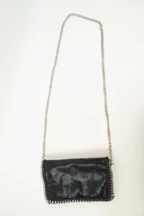 Cartera de mano negra con textura y correa de cadena plateada.