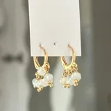 Aros dorados tipo argolla con dijes colgantes de cuentas rojas y cristal facetado.