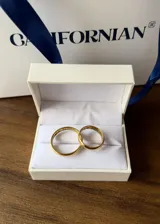 Par de alianzas de boda doradas con grabado de nombres y fecha.