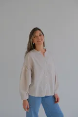 Camisa beige de lino con bordado de flores, cuello mao con volados y mangas largas abullonadas.