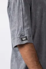 Remera oversize de algodón pesado, color gris oscuro con efecto lavado 'snow' que le da un aspecto gastado y único. Presenta cuello redondo y costuras vistas en hombros y mangas.