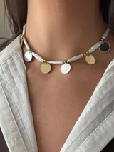 Collar corto con perlas de río naturales, cuentas metálicas de acero quirúrgico, medallitas bañadas en plata y oro y mostacillas. Se cierra con cadena de acero quirúrgico y ganchito para regular el largo.