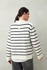 Sweater de punto a rayas horizontales color beige y blanco, con cuello bote y corte holgado.