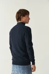 Sweater gris de punto con medio cierre, cuello alto y logo bordado en el pecho.