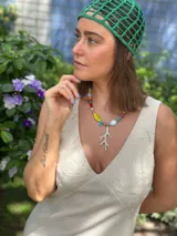 Collar corto con cuentas de cristal checo, cerámica y piedras reconstituidas de colores. Incluye separadores de acero quirúrgico y un dije plateado en forma de coral. Se cierra con cadena de acero quirúrgico para regular el largo.