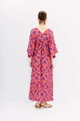 Vestido largo de viscosa estampada en tonos naranja y violeta. Tiene mangas al codo, calce holgado y recorte en la cintura con frunces.