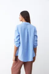 Camisa celeste de lino con mangas 3/4 y dos bolsillos frontales.