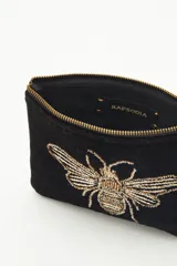 Bolso de mano tipo sobre rectangular de terciopelo negro con cierre dorado y flecos de mostacillas doradas. Presenta un bordado de abeja con canutillos dorados en el frente.