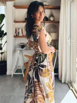Vestido largo con estampado de hojas en tonos marrones, amarillos y verdes. Tiene escote cruzado y cinturón de la misma tela.