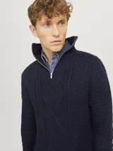 Sweater de punto con cuello alto y cierre metálico a la mitad del pecho. Tejido con diseño de trenzas y rombos.