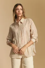 Camisa de manga larga color beige claro con bordado de flores blancas en relieve, cuello clásico y corte holgado.