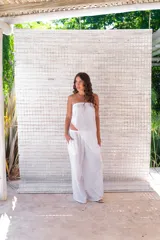 Conjunto de dos piezas color beige claro, compuesto por un top strapless con bajo asimétrico y un pantalón ancho de tiro alto.