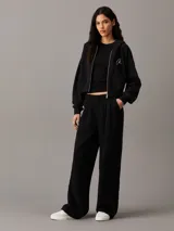 Buzo negro cropped con capucha y cierre frontal de cremallera metálica. Tiene bolsillos de parche en la cintura y logo de Calvin Klein bordado en el pecho.