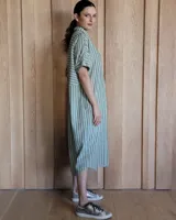 Vestido túnica celeste de lino con rayas verticales blancas, corte recto, cuello camisero y mangas cortas.