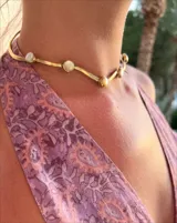 Gargantilla rígida dorada con incrustaciones de nácar.