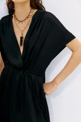 Vestido corto negro de poliéster, con escote cruzado, mangas cortas y cintura elastizada.