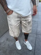 Bermuda de jean color beige con estampado tipo camuflaje en tonos marrones.