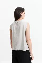 Blusa sin mangas color beige con lazo frontal y textura liviana.
