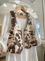 Chaleco con estampado de vaca en tonos marrones y beige, con botones al frente.