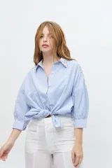 Camisa a rayas verticales color beige y blanco, con cuello clásico, manga larga abullonada y bordados de strass en hombros y cuello.