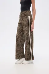 Pantalón ancho de tiro medio con estampado animal print de leopardo en tonos marrones y negros. Presenta una franja lateral deportiva en blanco y negro.
