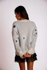 Buzo color crudo con escote en V y apliques de círculos marrones.