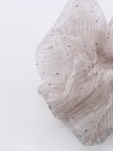 Colero de tela color crudo con pequeñas lentejuelas plateadas.