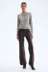 Cárdigan gris de punto suave con cuello redondo y botones metálicos dorados en el frente. Tiene remate acanalado en cuello, puños y bajo.